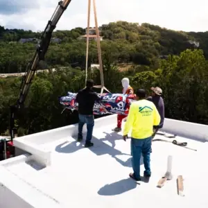 Crew working on a flat roof with a crane lift